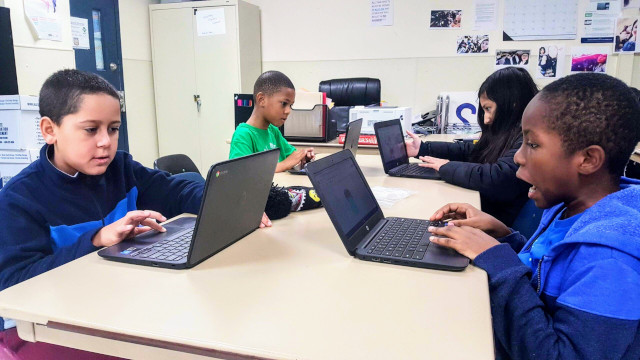 Four students are having fun coding their websites on a table.
