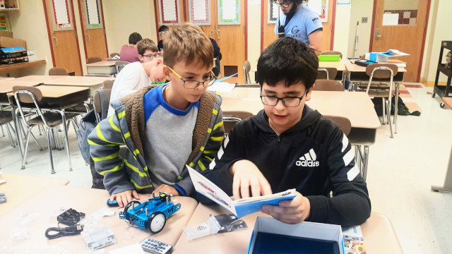 Two students learn how to build a robot.