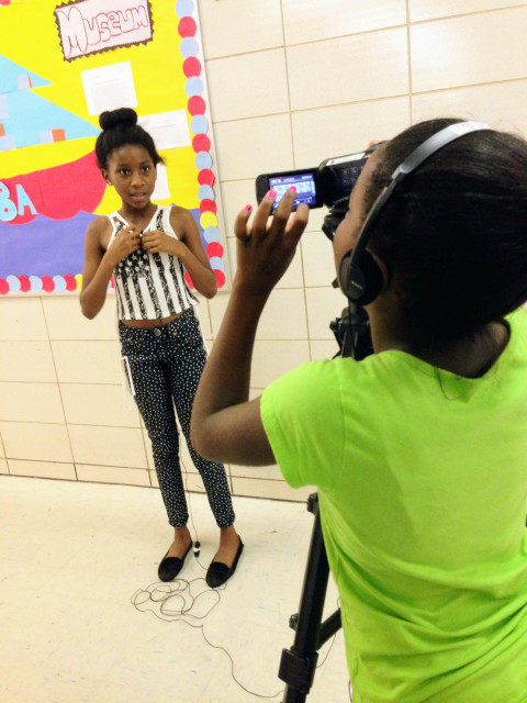 Middle schools student operated camera for while interviewing a student.