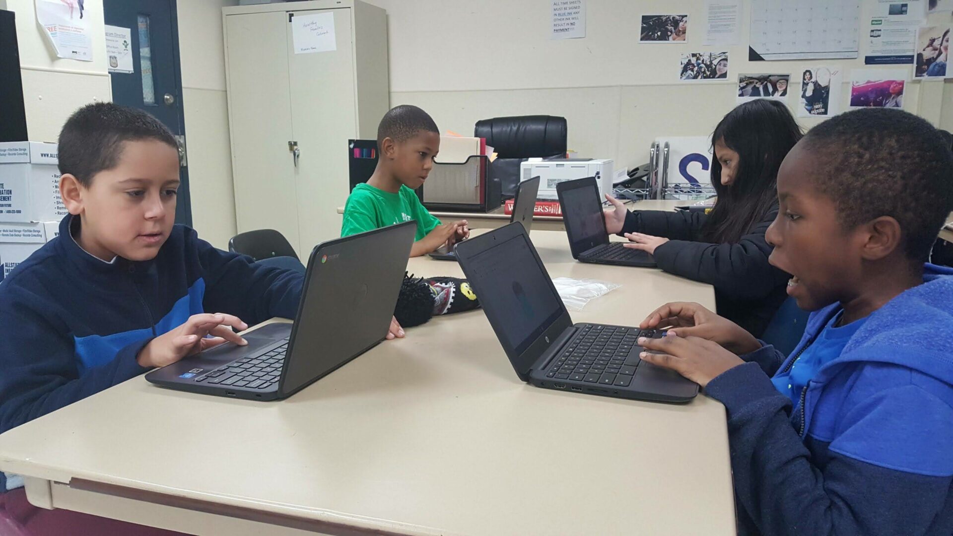 Four students are having fun coding their websites on a table.