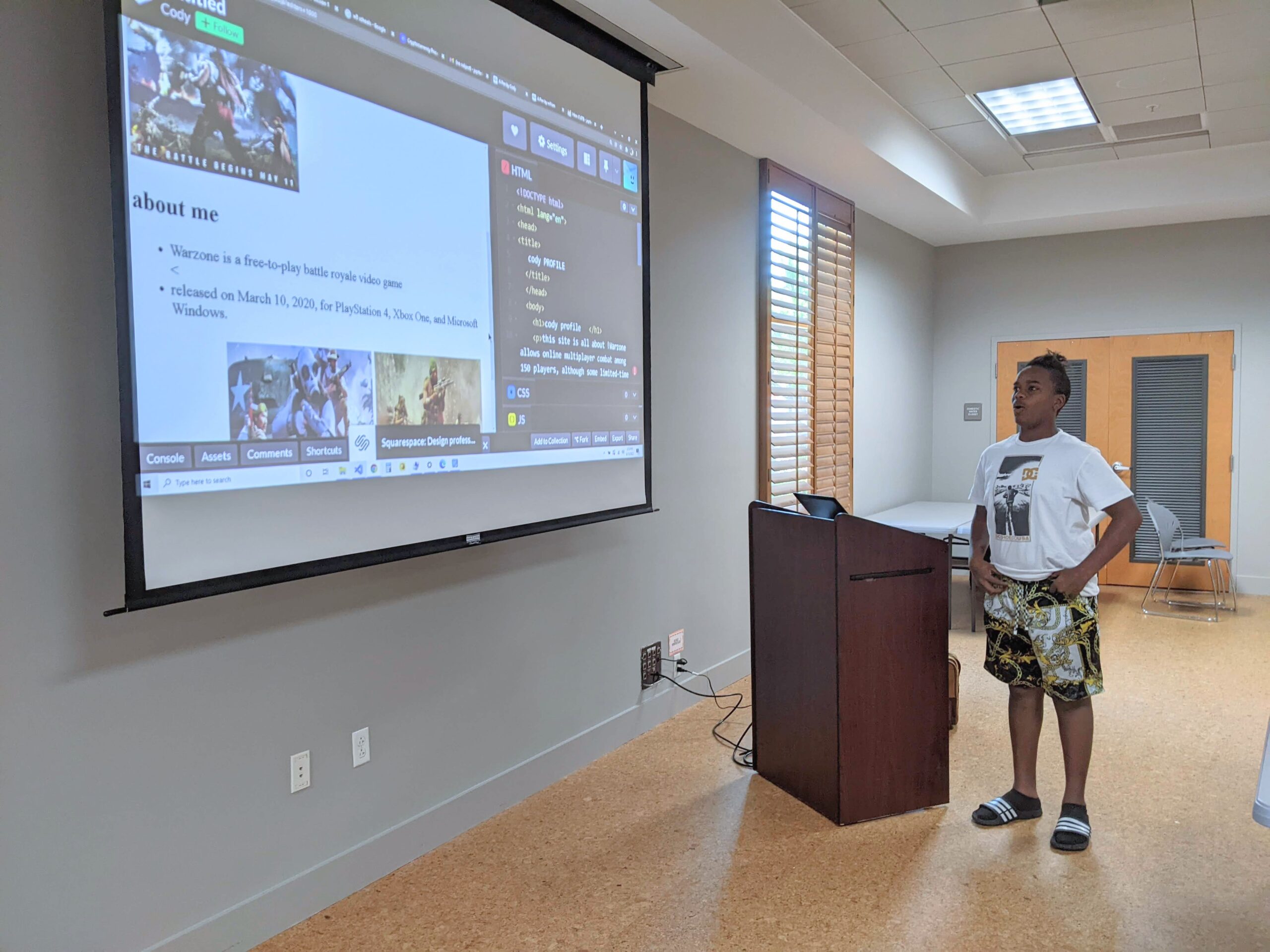 Teenage student presents his website and code on a projection screen.